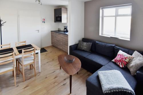 a living room with a couch and a table and a kitchen at Breidamyri Farm Apartments in Laugar