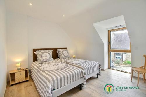 a bedroom with a bed with a striped comforter and a window at La grange in Ploeren