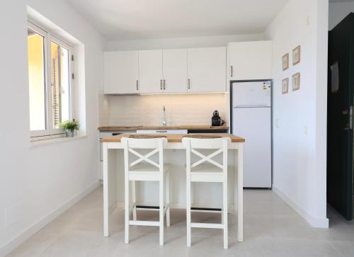 una cucina con mobili bianchi e un frigorifero bianco di Petit Paradis a Son Bou