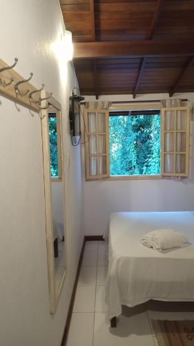 a bedroom with a bed and a mirror and a window at Pitanga Ilha Grande in Abraão