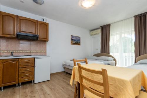 カシュテラにあるApartments Dinoのベッドが2つある部屋にテーブル付きのキッチンがある