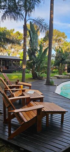 a group of wooden benches sitting on a deck next to a pool at Complejo Aramis Chapadmalal in Chapadmalal