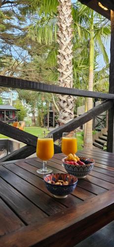 two glasses of orange juice and bowls of fruit on a wooden table at Complejo Aramis Chapadmalal in Chapadmalal