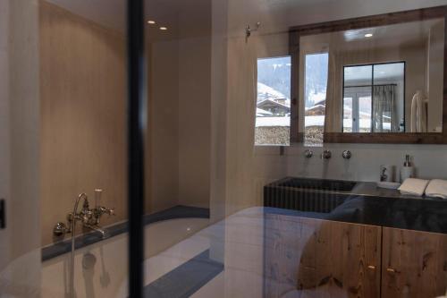 une salle de bain avec une baignoire, un lavabo et un miroir dans l'établissement Appartement Flocon de Nell, à Megève