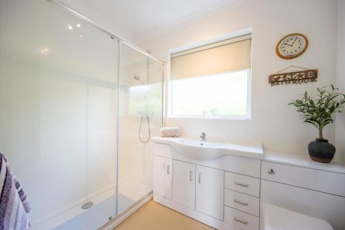 a bathroom with a sink and a shower and a clock at Everglades, Reydon in Reydon