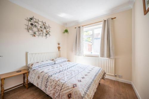 a white bedroom with a bed and a window at Everglades, Reydon in Reydon