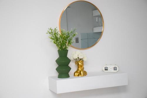 a mirror on a shelf with a vase and flowers at Optimum Stay Self Catering Accommodation - Junior Suite in Parow