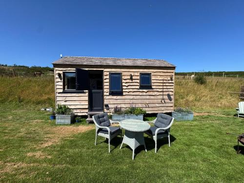a tiny house with a table and chairs in the yard at The Cabin at Salcombe Farm in Salcombe