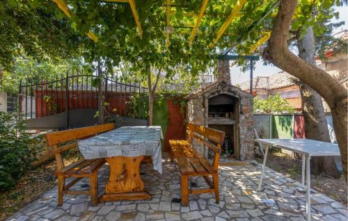 a table and two benches and a table and a stone oven at 4 Bedroom Awesome Apartment In Sveti Juraj in Sveti Juraj