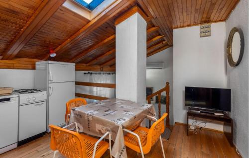 a kitchen with a table with orange chairs and a television at 4 Bedroom Awesome Apartment In Sveti Juraj in Sveti Juraj