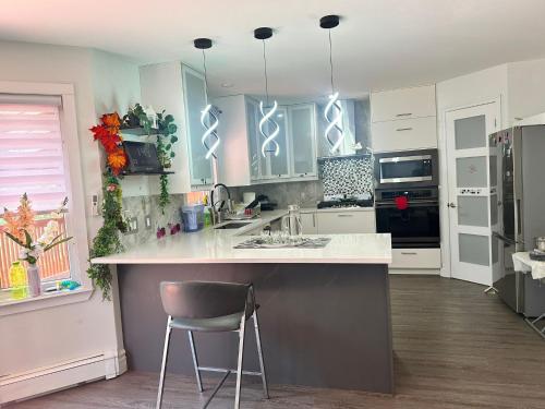 a kitchen with white cabinets and a counter with a chair at 3-Bedroom Modern House in Halifax