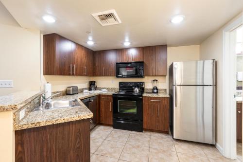 a kitchen with wooden cabinets and a stainless steel refrigerator at The Grandview at Las Vegas in Las Vegas