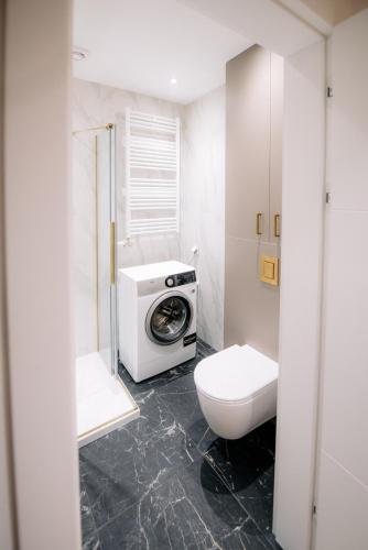 a bathroom with a toilet and a washing machine at obywatelska apartament free parking KLIMA in Łódź