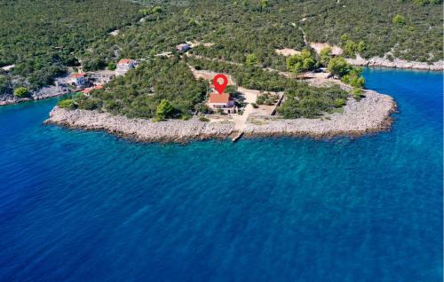 an island in the water with a red house on it at Holiday Home Zastrazisce With Sea View 04 in Selca kod Bogomolja