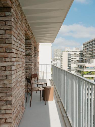 a balcony with two chairs and a brick wall at Edgar Suites - Église in Paris