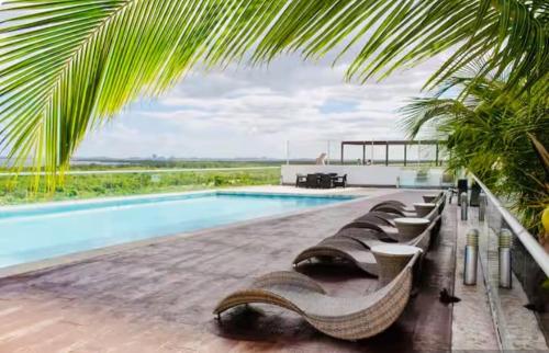 a pool with a bunch of lounge chairs next to it at Lovely loft with pool in center! in Cancún