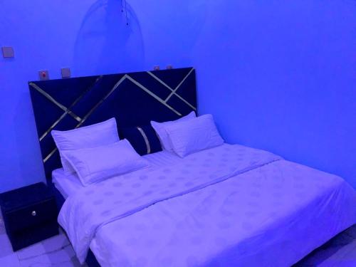 a bed with white sheets and pillows in a blue room at Royal Suite in Jidu