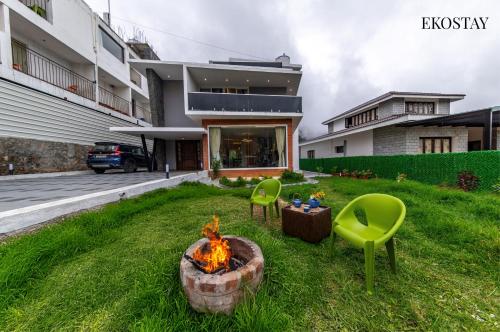 a backyard with a fire pit and two green chairs at EKOSTAY - Amber Villa in Kodaikānāl