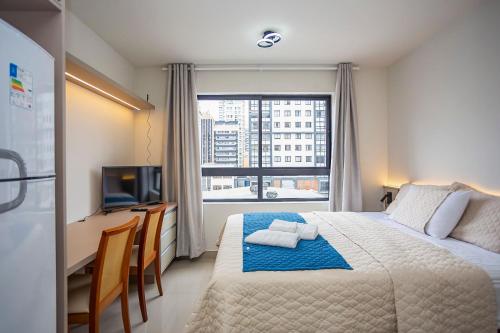 a bedroom with a bed with a desk and a window at MUV proximo ao shopping in Curitiba