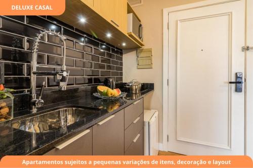 a kitchen with a sink and a black tiled wall at Century Park by My Way in Porto Alegre