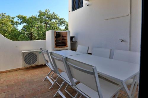 une table blanche et des chaises sur une terrasse avec une fenêtre dans l'établissement Villa Vale Do Lobo 2 Townhouse 3 Bedroom Close To Amenities And Beach, à Vale do Lobo