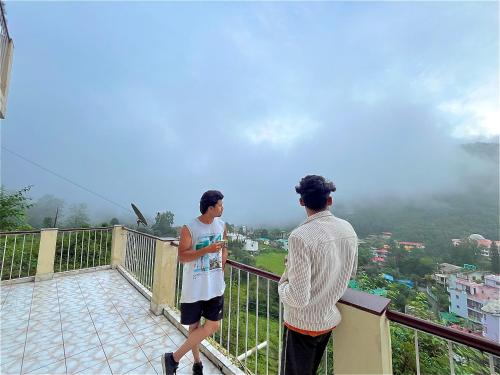 BhowāliにあるSoul Homestayの二人の男が街を見下ろすバルコニーに立っている