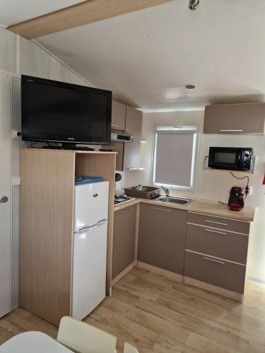a small kitchen with a refrigerator and a tv at Mobil home en Provence - Camping 4 étoiles- 2 chambres -4 à 6 pers-clim-terrasse-TV in Cadenet