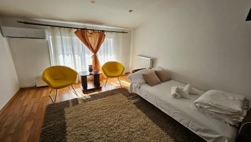 a bedroom with a bed and two yellow chairs at Apartamente elegante in regim hotelier in Iaşi