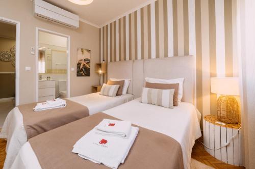 two beds in a hotel room with towels on them at Casa da Praia in Zambujeira do Mar