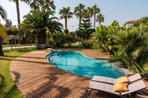 une piscine dans une cour avec des palmiers dans l'établissement Chambre Canopée - maison exotique, à Hyères