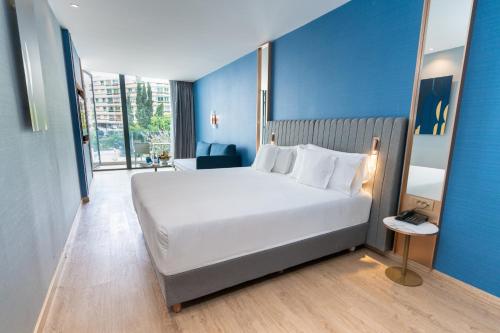 a bedroom with a large white bed and a blue wall at Barceló Tanger in Tangier