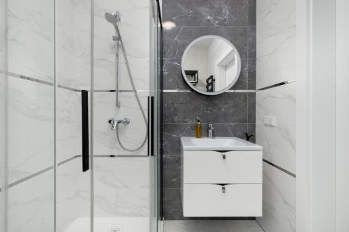 a bathroom with a shower and a sink and a mirror at Sosnowa by Solarento in Mielno