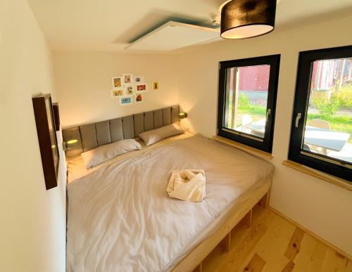 a large bed in a room with two windows at Haus 2 am Grimnitzsee - hochwertiges Design, mit eigenem Garten und nah am See in Joachimsthal