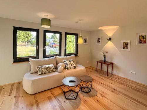 a living room with a couch and two windows at Haus 2 am Grimnitzsee - hochwertiges Design, mit eigenem Garten und nah am See in Joachimsthal