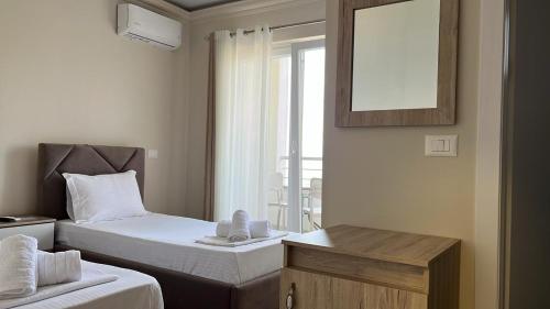 a bedroom with two beds and a mirror and a window at Hotel DEMOLI in Pogradec