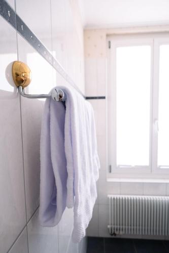 a white towel hanging on a towel rack in a bathroom at Room's at HAUS am SEE direkt am Thunersee gelegen mit SELF CHECK IN & digitaler Rezeption in Oberhofen am Thunersee