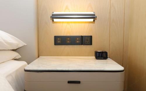 a nightstand with a clock on it next to a bed at Four Points by Sheraton Changsha, Meixi Lake in Changsha