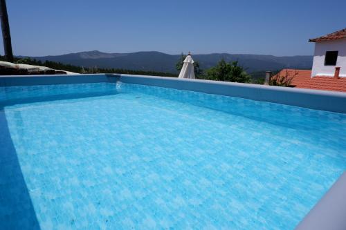 a large swimming pool with blue water at Casa de Montanha in Figueiró dos Vinhos