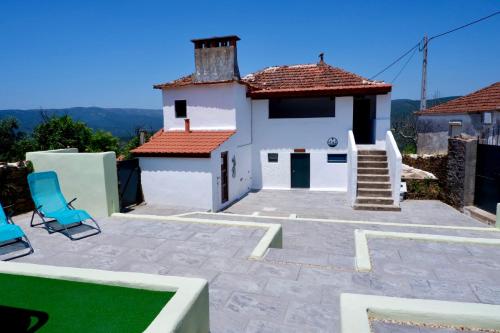 a patio with two chairs and a house at Casa de Montanha in Figueiró dos Vinhos