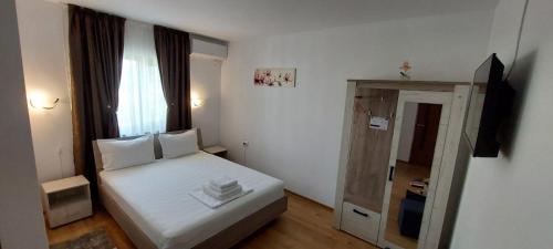 a small bedroom with a white bed and a window at Casa Militaru in Murighiol