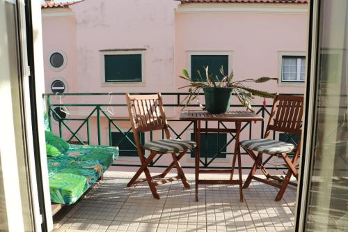 a balcony with a table and two chairs and a plant at Fantastic apartment with pool access in Pataias