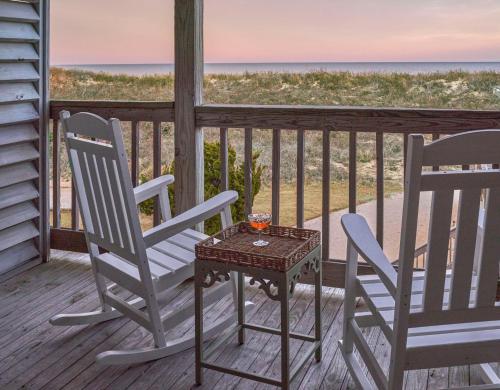 two chairs and a table on a porch with the ocean at The Sanderling in Duck