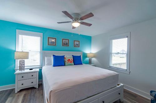 a bedroom with blue walls and a bed with a ceiling fan at The Sanderling in Duck