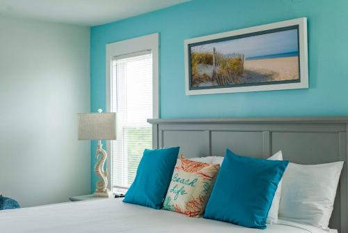 a bedroom with blue walls and a bed with pillows at The Sanderling in Duck