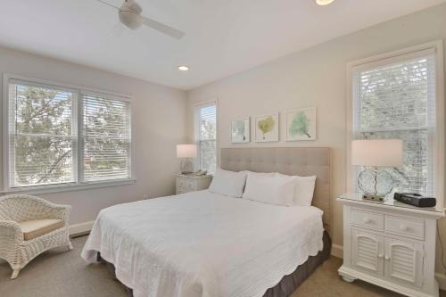 a bedroom with a white bed and two windows at The Sanderling in Duck