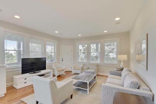 a living room with white furniture and a flat screen tv at The Sanderling in Duck
