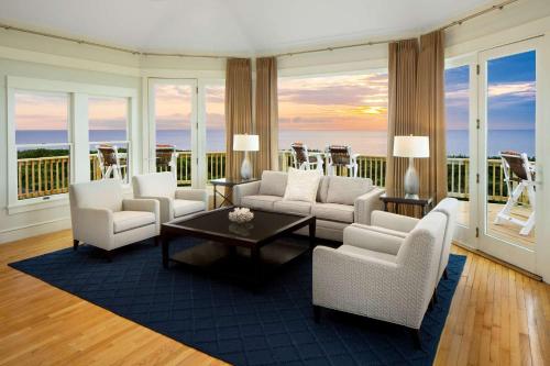 a living room with white furniture and a view of the ocean at The Sanderling in Duck