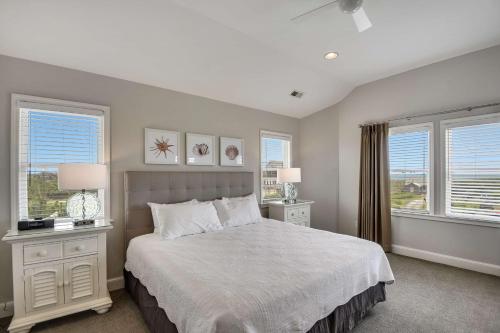 a bedroom with a large bed with two windows at The Sanderling in Duck