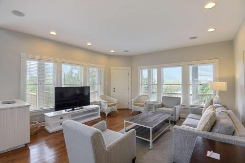 a living room with a tv and a couch and chairs at The Sanderling in Duck