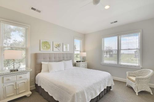 a white bedroom with a bed and two windows at The Sanderling in Duck